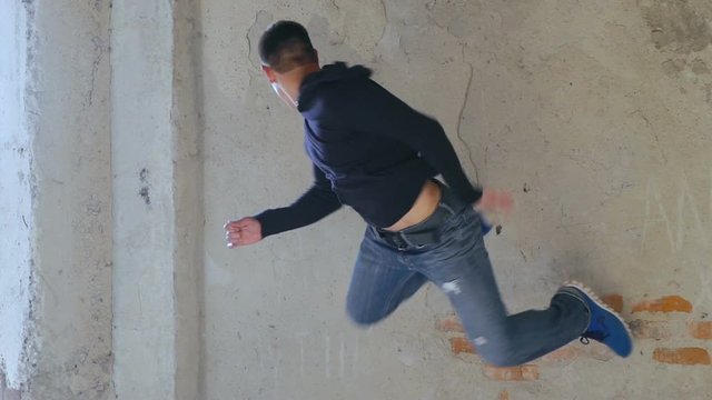 A free runner back flips off a wall. Slowly