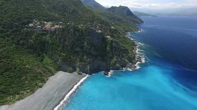 Aerial: Flight over ancient village of Nonza, black beach and spectacular cliffs, typical landscape on Corsica island, France, Europe 