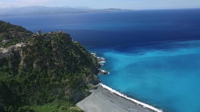 Aerial: Flight over ancient village of Nonza, black beach and spectacular cliffs, typical landscape on Corsica island, France, Europe 