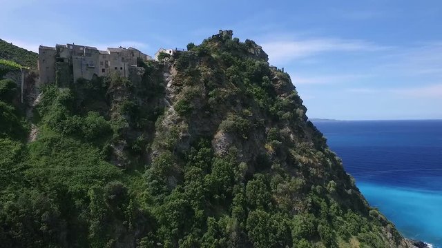 Aerial: Flight over ancient village of Nonza, black beach and spectacular cliffs, typical landscape on Corsica island, France, Europe 