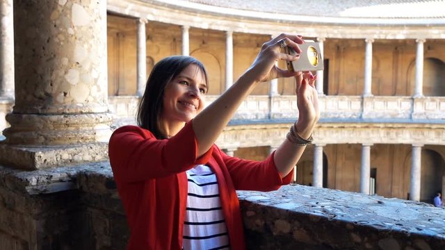 Woman taking selfie photo during sightseeing old amphitheatre building, super slow motion
