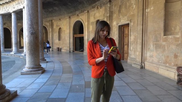 Young woman sightseeing with smartphone old amphitheatre building, super slow motion
