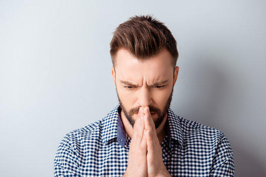 Portrait of young bearded man in shirt praying and waiting