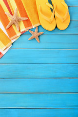 Summer beach background border flip flops starfish sunbathing vacation holiday accessories on old weathered blue wood deck decking or boardwalk photo vertical
