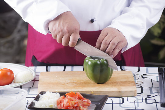 Chef cutting green bell pepper with knife before cooking