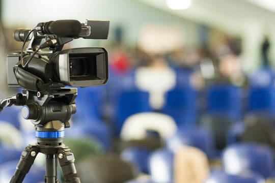 Front View of Professional Videocamera. Positioned Against Blurred Background