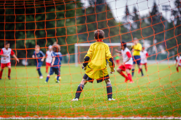 Fototapeta premium Young soccer goalie defending the net in the rain