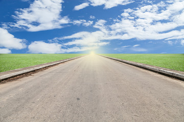 asphalted road with green grass blue sky background.