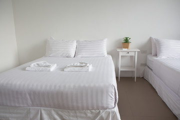 white king size bed, two pillows, towel and tree pot plant in bedroom for rest and relax, feel comfortable