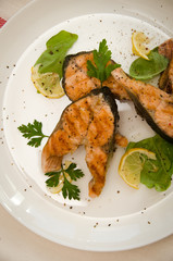 several salmon steaks white round plate spices