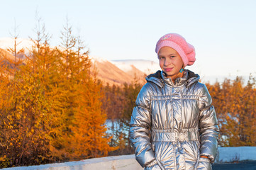 Girl teenager in silver down jacket in autumn tundra
