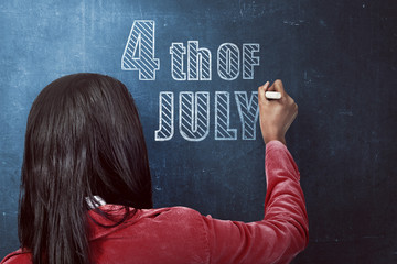 Woman write 4th of july on the chalkboard