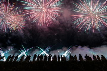 Group of people enjoying fireworks show in a carnival or holiday. People in silhouette.