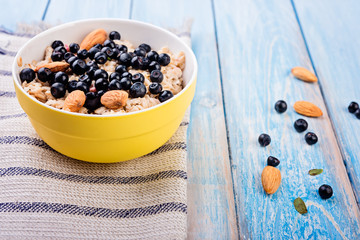 Oatmeal with almonds and berries in a  bowl on blue rustic  background. diet breakfast.