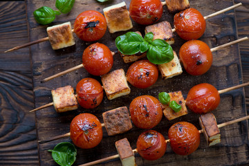 Grilled cherry tomatoes and cheese on skewers, top view, closeup