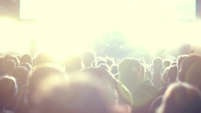 Iconic night rock concert front row crowd cheering slomo 100p.Night rock concert.People cheer move lift and clap their hands in unison against the strobing stage lights.