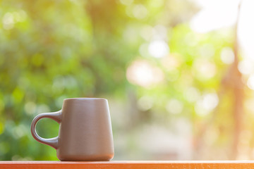 brown ceramic coffee cup with blur garden background