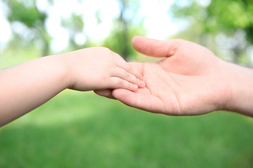 Adult and child hands on natural background