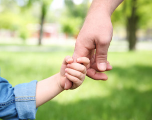 Adult and child hands on natural background