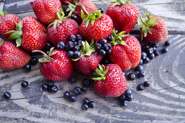 Newly collected fresh blueberries and strawberries on wooden background. Summer organic berry over wood.