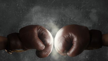 Fototapeta na wymiar Two old brown boxing gloves hit together