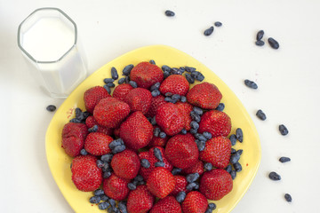 Dish of strawberries and honeysuckle with glass of milk