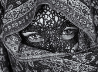 Young woman covered with a headscarf and carnival mask.
