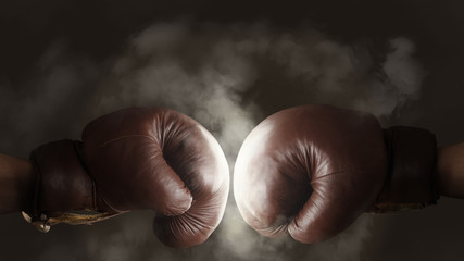 Two old brown boxing gloves hit together - Powered by Adobe