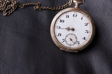 old clock on a background of black leather