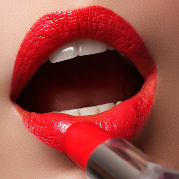 Beauty lips. Beautiful lips close-up, great idea for the advertising of cosmetics. Extreme close up on model applying red lipstick. Makeup. Professional fashion retro make-up. Red lipstick

