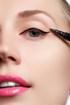 Beautiful woman with bright make up eye with sexy black liner makeup. Fashion arrow shape. Chic evening make-up. Makeup beauty with brush eye liner on pretty woman face

