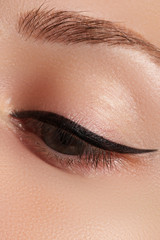 Cosmetics and make-up. Beautiful female eye with sexy black liner makeup. Fashion big arrow shape...