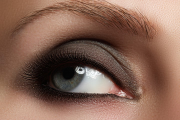 Obraz premium Macro shot of woman's beautiful eye with extremely long eyelashes. Sexy view, sensual look. Fashion smoky makeup.