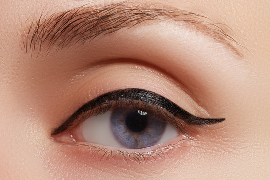 Cosmetics and make-up. Beautiful female eye with sexy black liner makeup. Fashion big arrow shape on woman's eyelid. Chic evening make-up
