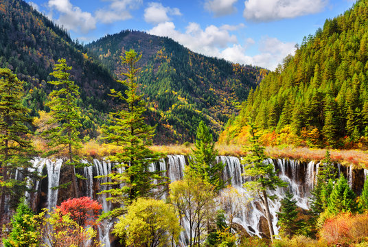 The Nuo Ri Lang Waterfall (Nuorilang) among wooded mountains
