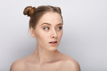 Portrait of a young woman with funny hairstyle and bare shoulders act the ape against white studio background