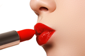 Extreme close up on model applying red lipstick. Make-up