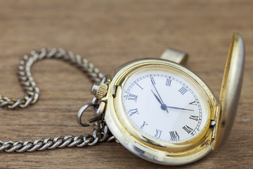 Old pocket watch on wood background.