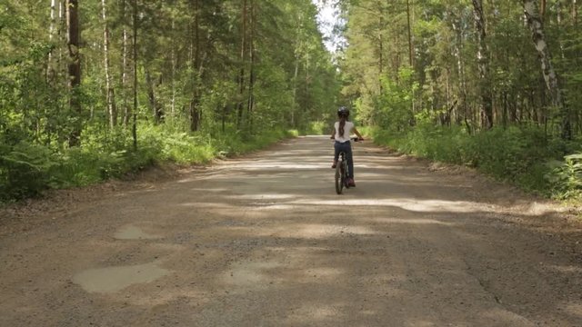 little girl rides her bike on a forest trail