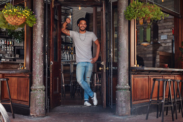 Smiling young man standing at the door of a cafe