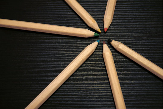 Sternf&ouml;rmig ausgelegte Buntstiften auf schwarzem Holztisch