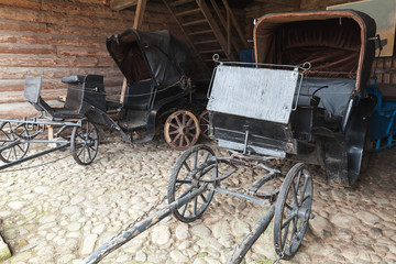 Fototapeta na wymiar Empty vintage black coaches stand in rural garage