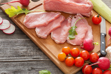 raw meat with fresh vegetables on wooden surface