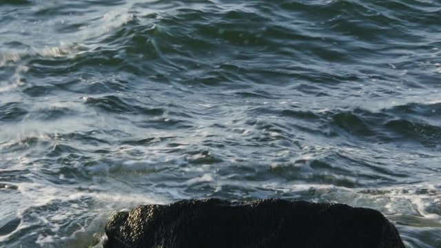 sea waves crush rocks , foam , whirl , deflect in different directions and retreat. Filmed at Baltic sea in Lithuania