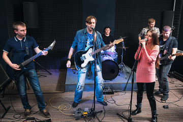 Fototapeta premium Music band alive performance on stage. Two vocalists sing, other member play on their musical instruments. Music group play their song.