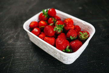 Fresh strawberry in the white basket on the black table