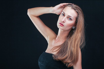 Obraz premium Pretty woman holding head in hands standing against black backgr