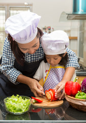 Asian mother teaching daughter making salad in kitchen,Cooking  concept of happy asian little girl and mother making salad 