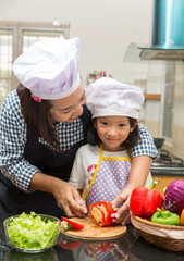 Asian mother teaching daughter making salad in kitchen,Cooking  concept of happy asian little girl and mother making salad 