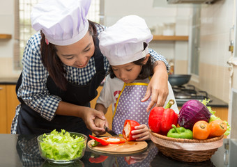 Asian mother teaching daughter making salad in kitchen,Cooking  concept of happy asian little girl and mother making salad 